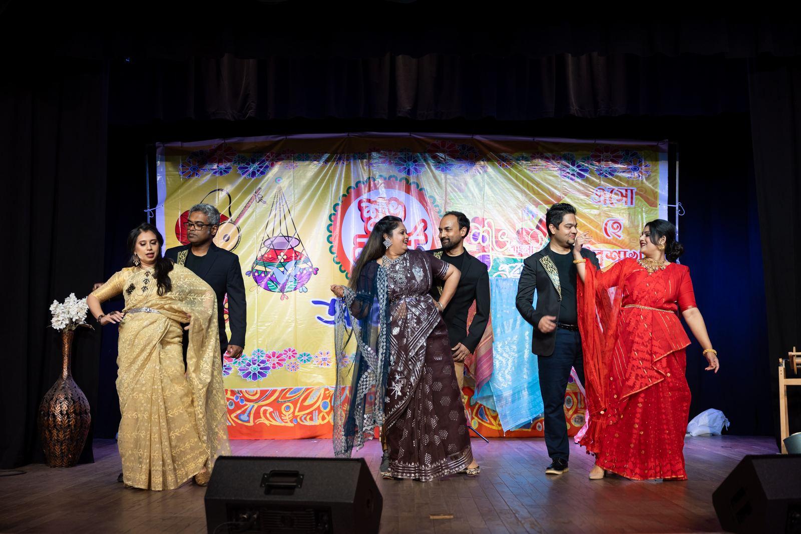 Emcees hosting the program on stage beside the Bangladeshi flag