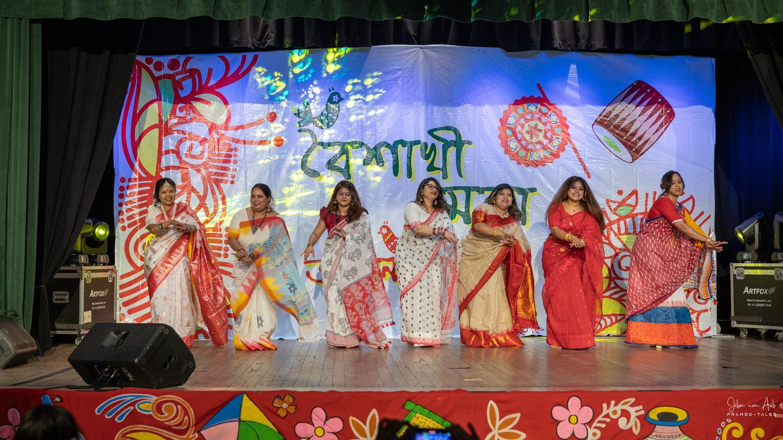 Seven women dancing in a line in sarees