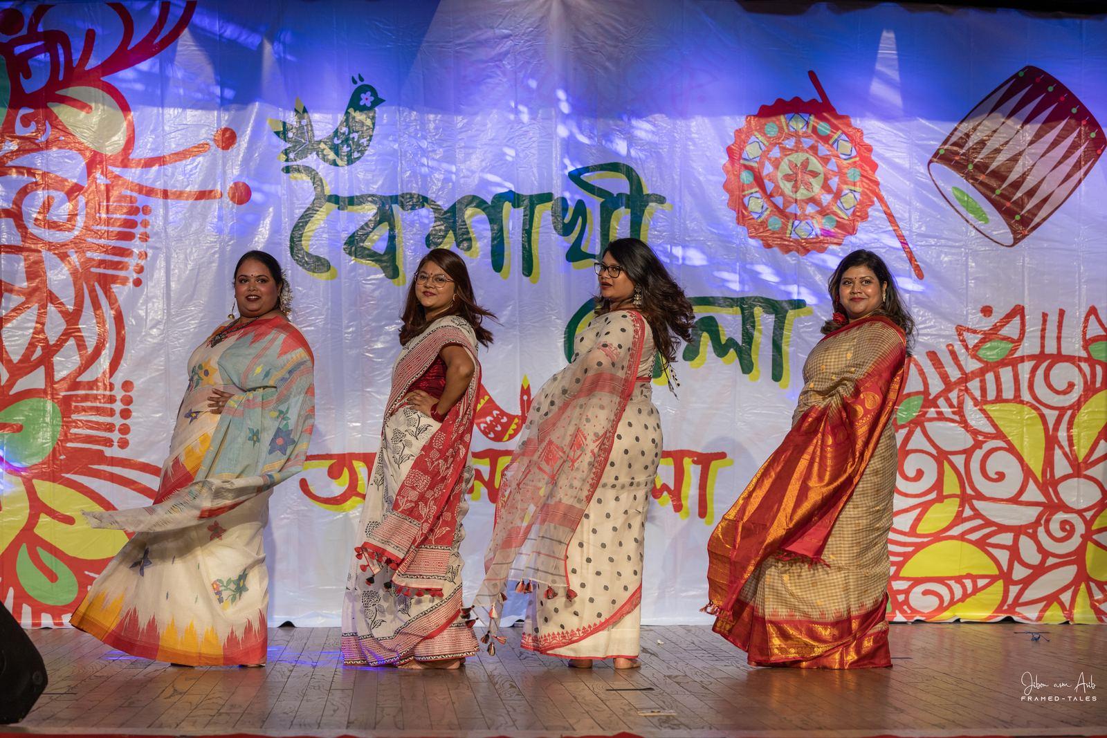 Four women mid-twirl, sarees flowing