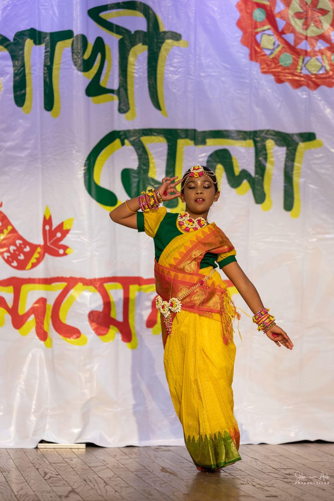 Girl in yellow-green saree dancing, saluting pose