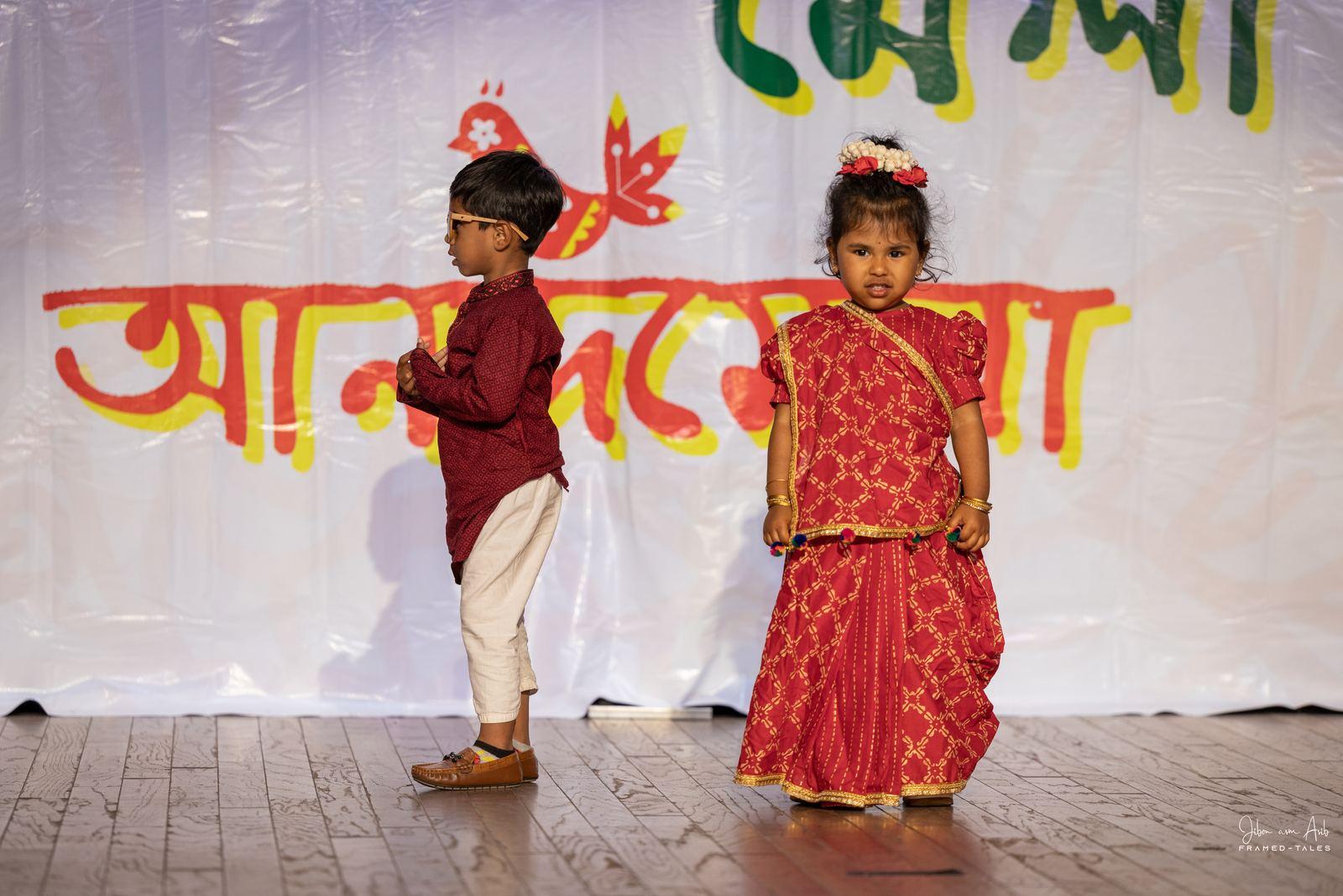 Toddler boy and girl in traditional dress on stage