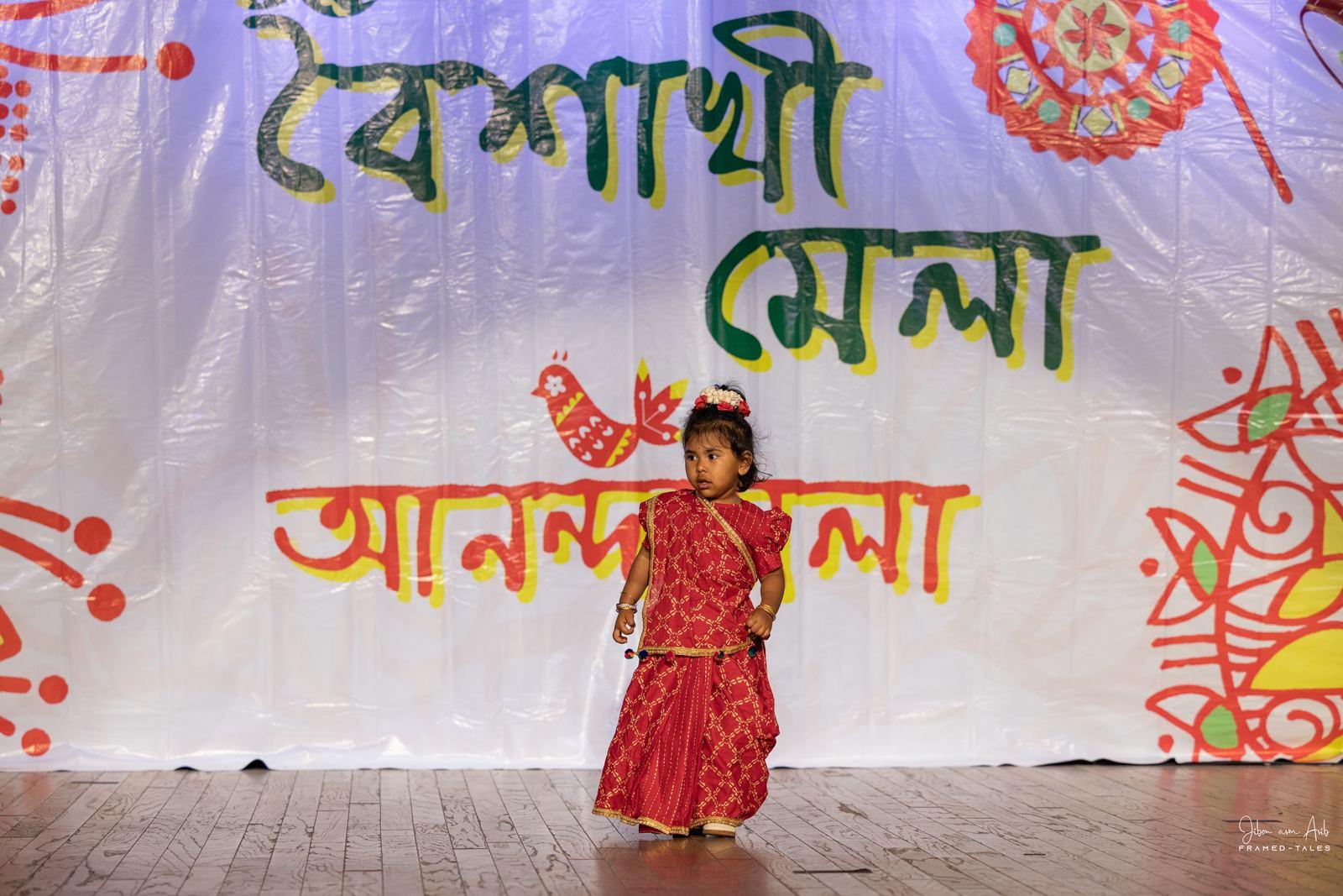 Toddler girl in red saree alone on stage