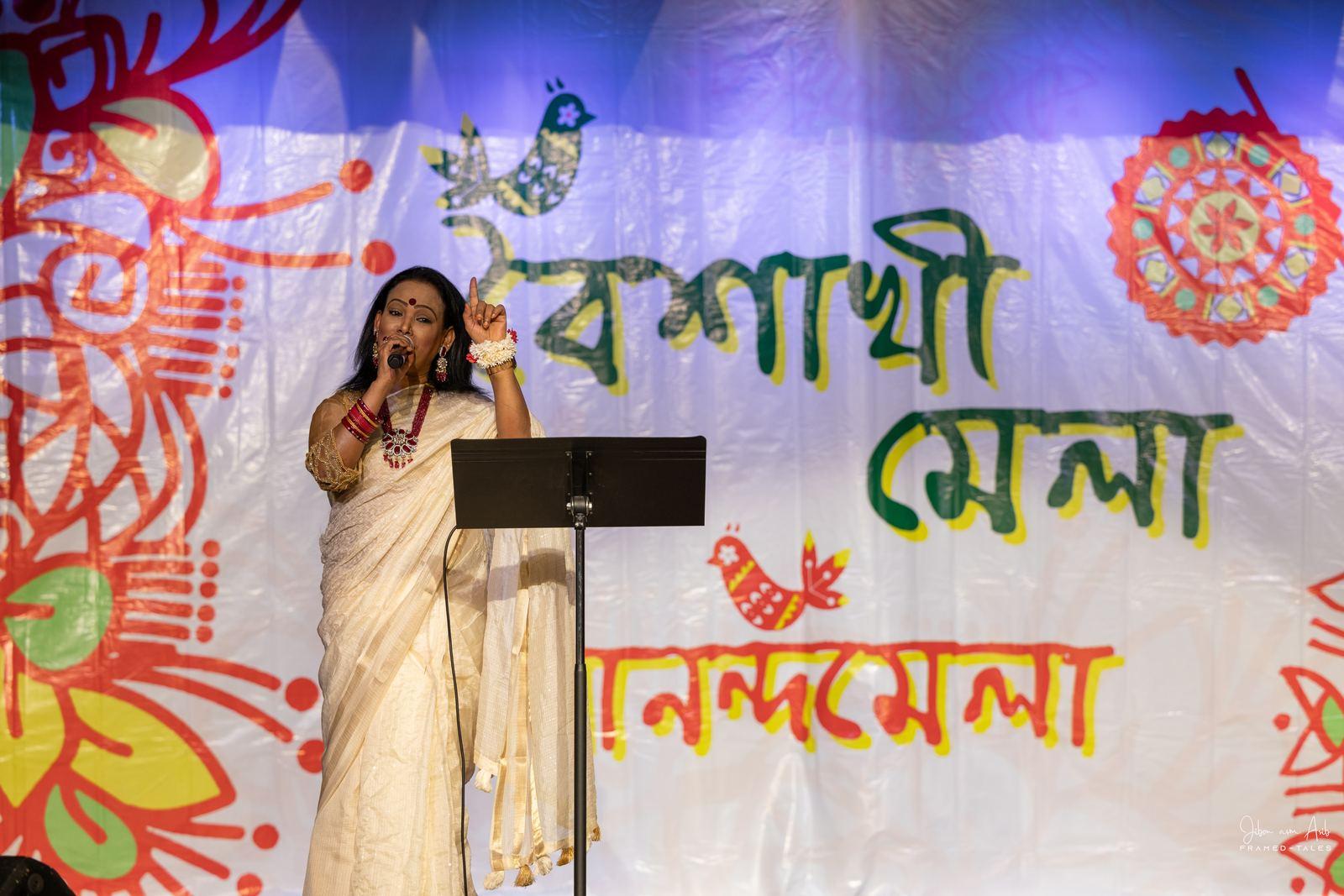 Female singer in white saree, pointing up, expressive