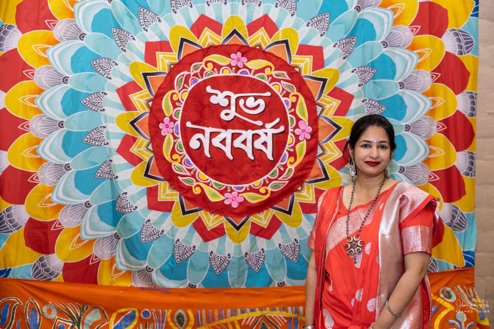 Woman in red saree before the colorful "Shubho Noboborsho" mandala photobooth